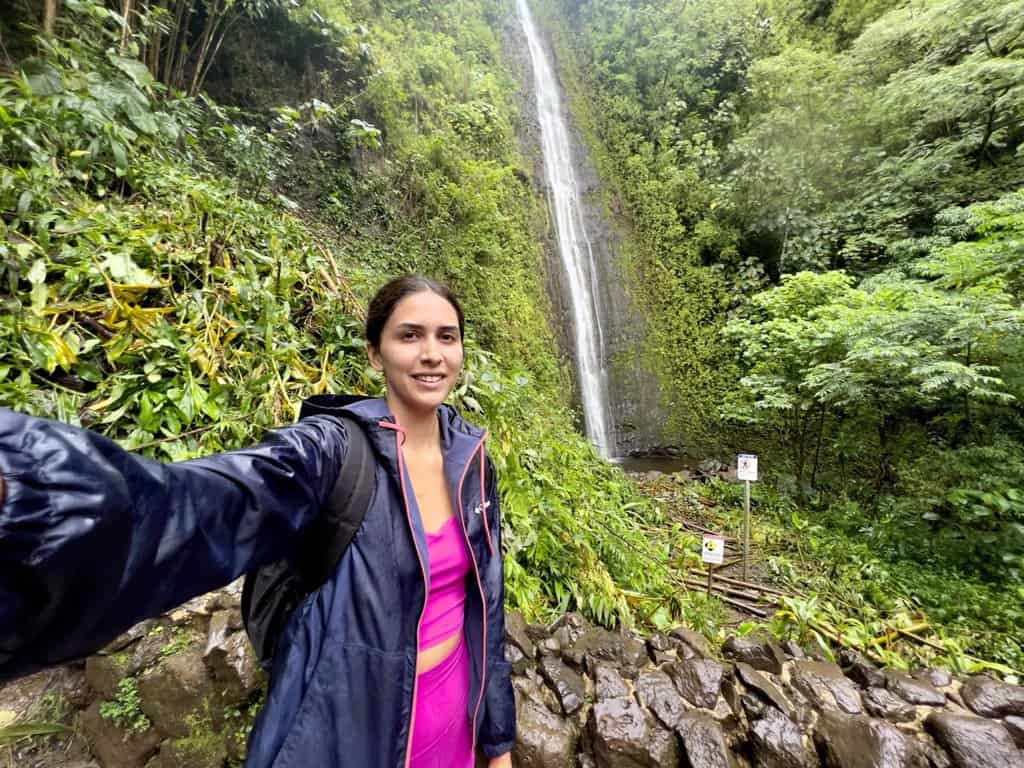 bridget gutierrez a travel blogger at a 100 foot water fall in oahu hawaii